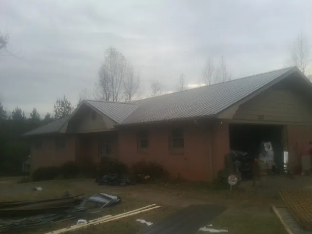 Gray metal roof on a stucco house with an attached garage in Metamora