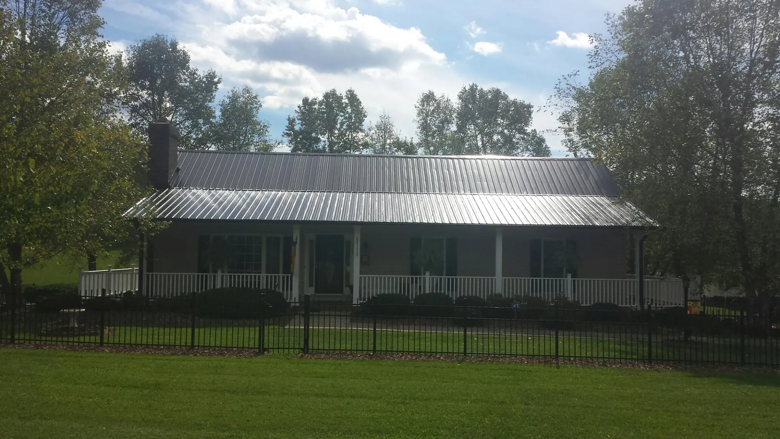 Gray metal roof on a brick ranch with a full width front porch — Gutter Guard Installation work by our crew in Metamora